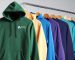 A multicoloured selection of hoodies hanging on a clothes rail
